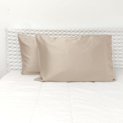 Duas fronhas bege em cama branca acolchoada