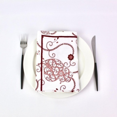 Jogo americano com padrão bordô sobre prato branco com talheres