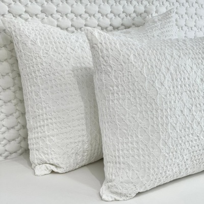Três almofadas brancas texturizadas sobre uma superfície branca