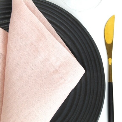 Conjunto de jantar com prato preto, guardanapo rosa e faca dourada