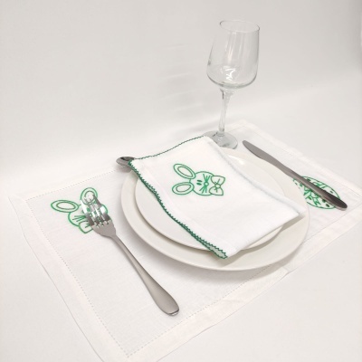 Jogo americano e guardanapo branco com bordado de coelho verde, prato branco, talheres e copo