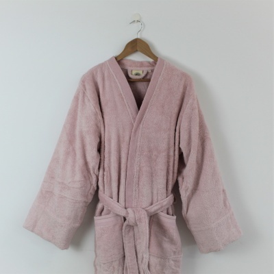 Robe de banho cor-de-rosa claro felpudo com cinto e bolsos pendurado num cabide
