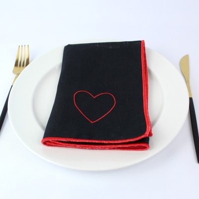 Guardanapo preto com borda e coração vermelhos sobre prato branco