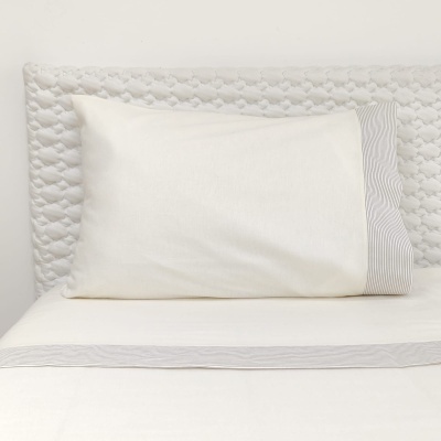 Almofada branca com detalhe riscado em cama com cabeceira acolchoada branca