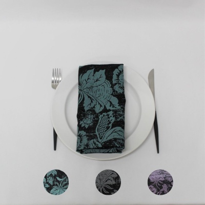 Mesa posta com prato branco, talheres com cabo preto e guardanapo verde e preto com padrão floral