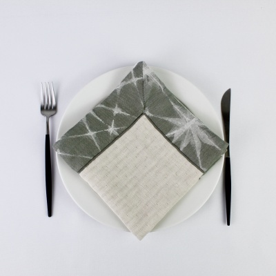 prato branco com guardanapos cinzento e creme, garfo e faca com cabo preto em mesa branca