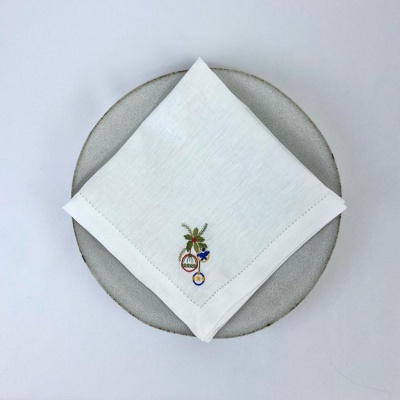 Guardanapo branco com bordado colorido sobre prato cinzento