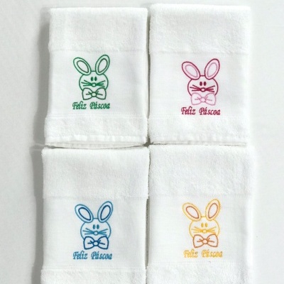 Quatro toalhas brancas com bordados de coelhos coloridos e texto 'Feliz Páscoa'
