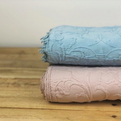 Dois tecidos dobrados azul claro e rosa claro com padrão floral sobre madeira clara