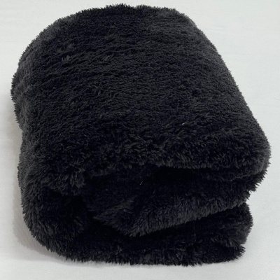 Cobertor preto felpudo dobrado sobre superfície branca