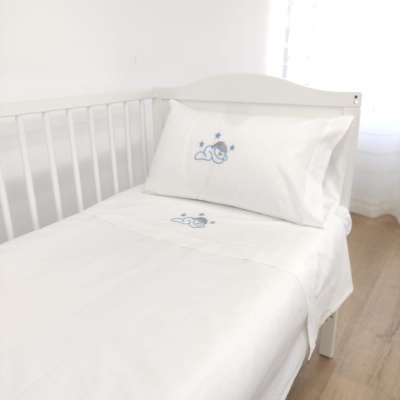 Cama de criança com roupa de cama branca bordada em azul