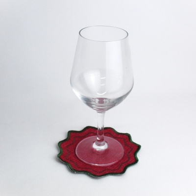 Copo de vinho transparente numa base de tecido vermelha com bordas verdes