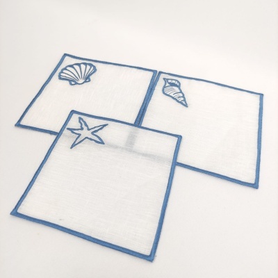 Três guardanapos brancos com bordas azuis e bordados marinhos