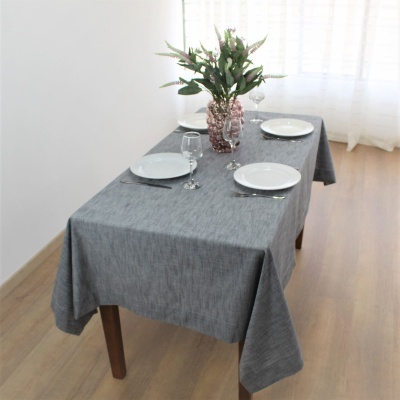 Mesa de jantar com toalha cinza e decoração com flores e louça branca