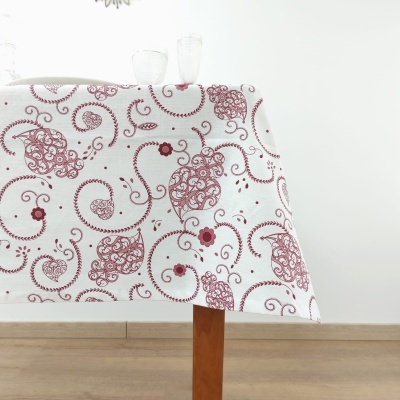 Toalha de mesa branca com padrão floral vermelho sobre mesa de madeira com taças