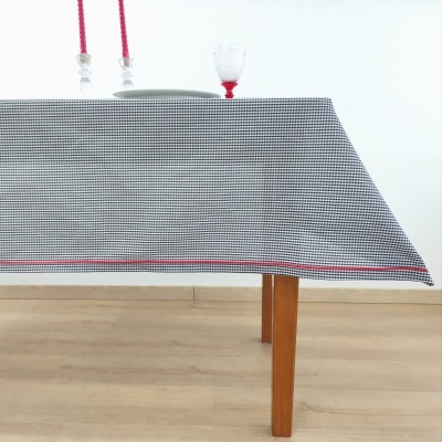 Toalha de mesa xadrez pequenas quadrículas preto e branco com faixa vermelha borda sobre mesa de madeira clara