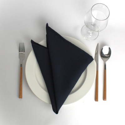 Talheres com cabo em madeira, guardanapo preto sobre prato branco e copo de vidro