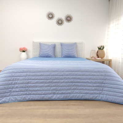 Cama com edredão azul claro e almofadas azuis num quarto decorado