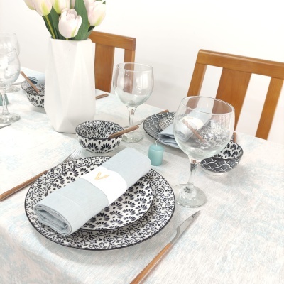 Conjunto de jantar preto e branco com flores, copos de vidro, e flor artificial branca em vaso branco.