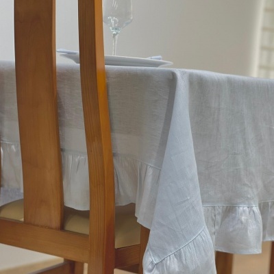 Toalha de mesa branca pendurada numa mesa de madeira com cadeira ao lado