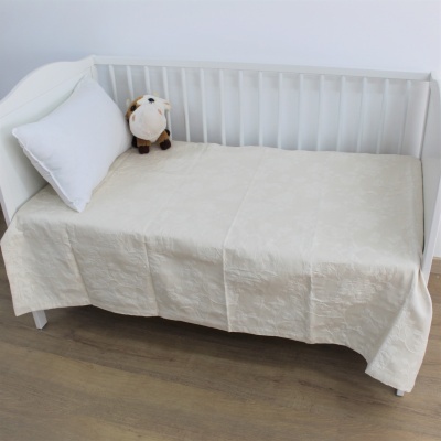 Cama de madeira branca com roupa de cama bege, almofada branca e peluche de vaquinha