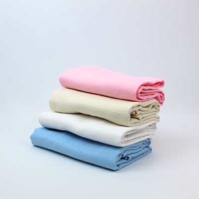 Quatro mantas ou toalhas empilhadas de cores rosa, bege, branco e azul sobre fundo branco