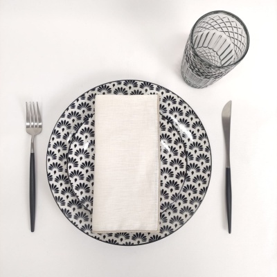 Conjunto de jantar com pratos brancos e padrão preto, talheres e copo decorado