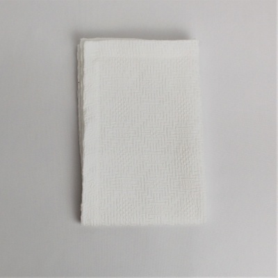 Toalha branca dobrada com padrão texturado sobre fundo cinza