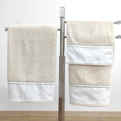 Duas toalhas creme com faixa branca em suporte metálico prateado