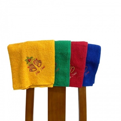 Quatro toalhas de banho coloridas com bordados de Natal penduradas numa cadeira de madeira