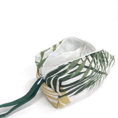 Estojo tecido com padrão de folhas verdes e douradas aberto