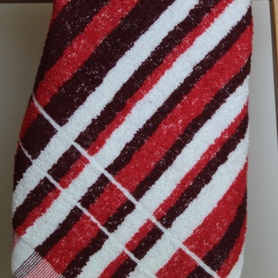 Toalha com riscas vermelhas, brancas e pretas pendurada em estrutura de madeira