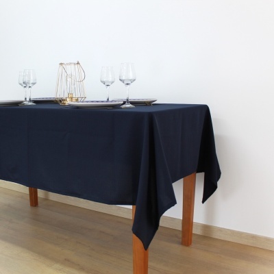 Mesa com toalha azul escura, copos e decoração de vela