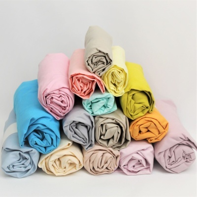 Rolos de tecidos coloridos empilhados em pirâmide sobre fundo branco