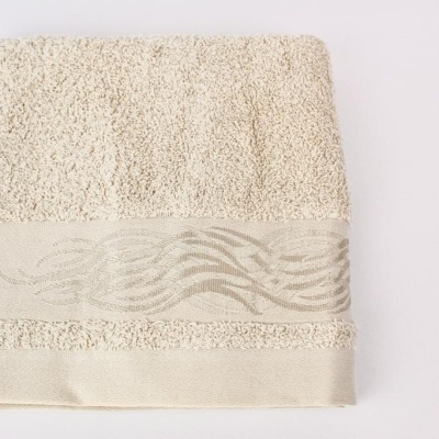 Toalha de banho creme com faixa decorativa texturada.