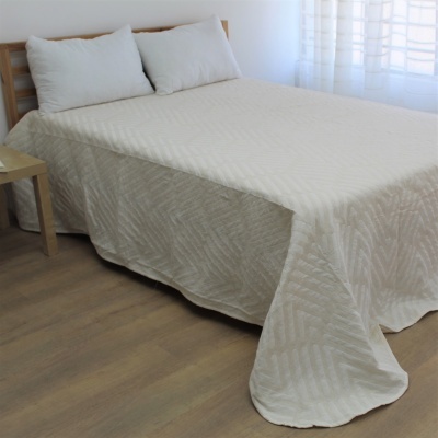 Colcha branca com padrão geométrico em cama de madeira com almofadas brancas