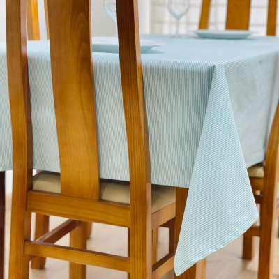 Mesa de madeira com toalha azul clara riscada e cadeiras de madeira com assento almofadado