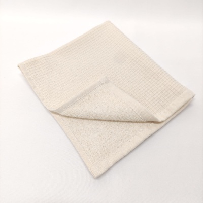 Toalha de mãos bege clara com duas texturas diferentes sobre fundo branco