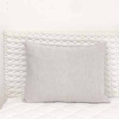 Almofada cinzenta com padrão sobre cama branca acolchoada