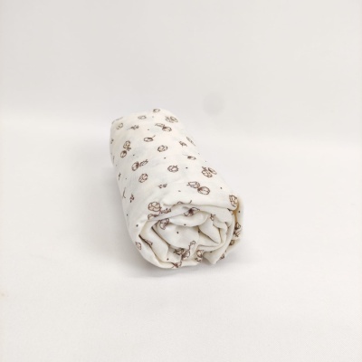 Manta branca enrolada com padrão de carrinhos castanhos e amarelos