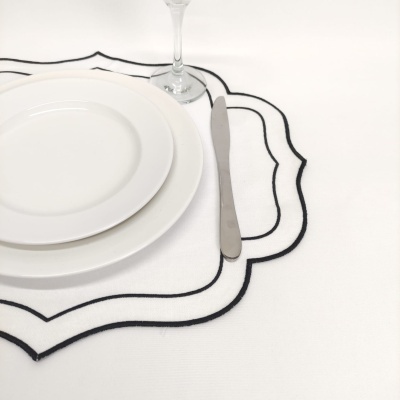 Conjunto de loiça branca com pratos e faca sobre guardanapo branco com borda preta