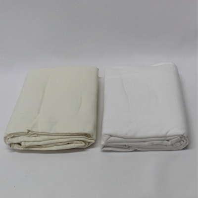 Tecidos dobrados em tons bege e branco sobre fundo branco