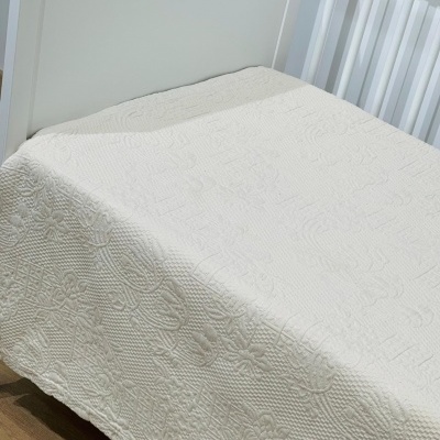 Colcha branca em cama com padrão em relevo