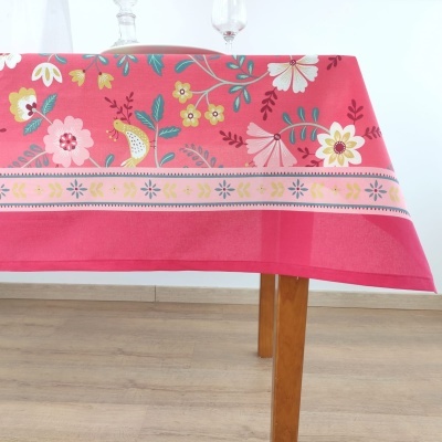 Toalha de mesa rosa com flores coloridas e borda decorativa, mesa de madeira clara