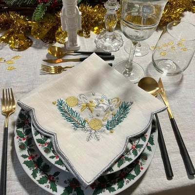 Mesa de Natal com loiça decorada, guardanapo bordado e talheres preto e dourado