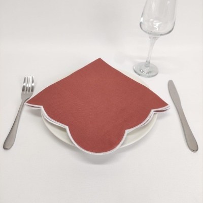 Conjunto posto de mesa com guardanapo vermelho, prato branco, talheres metálicos e taça de vidro