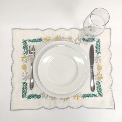 Mesa posta com guardanapo bordado, prato branco, talheres e copo de vidro