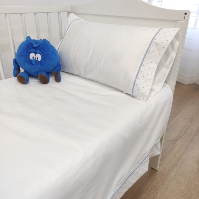 Cama infantil branca com roupa de cama branca com detalhes azuis e boneco azul
