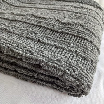 Manta cinza de malha com padrão texturizado dobrada