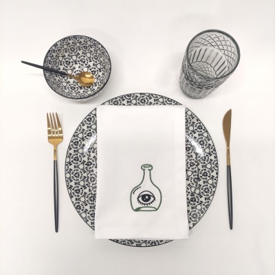 Conjunto de mesa com prato, tigela, talheres e copo sobre pano branco